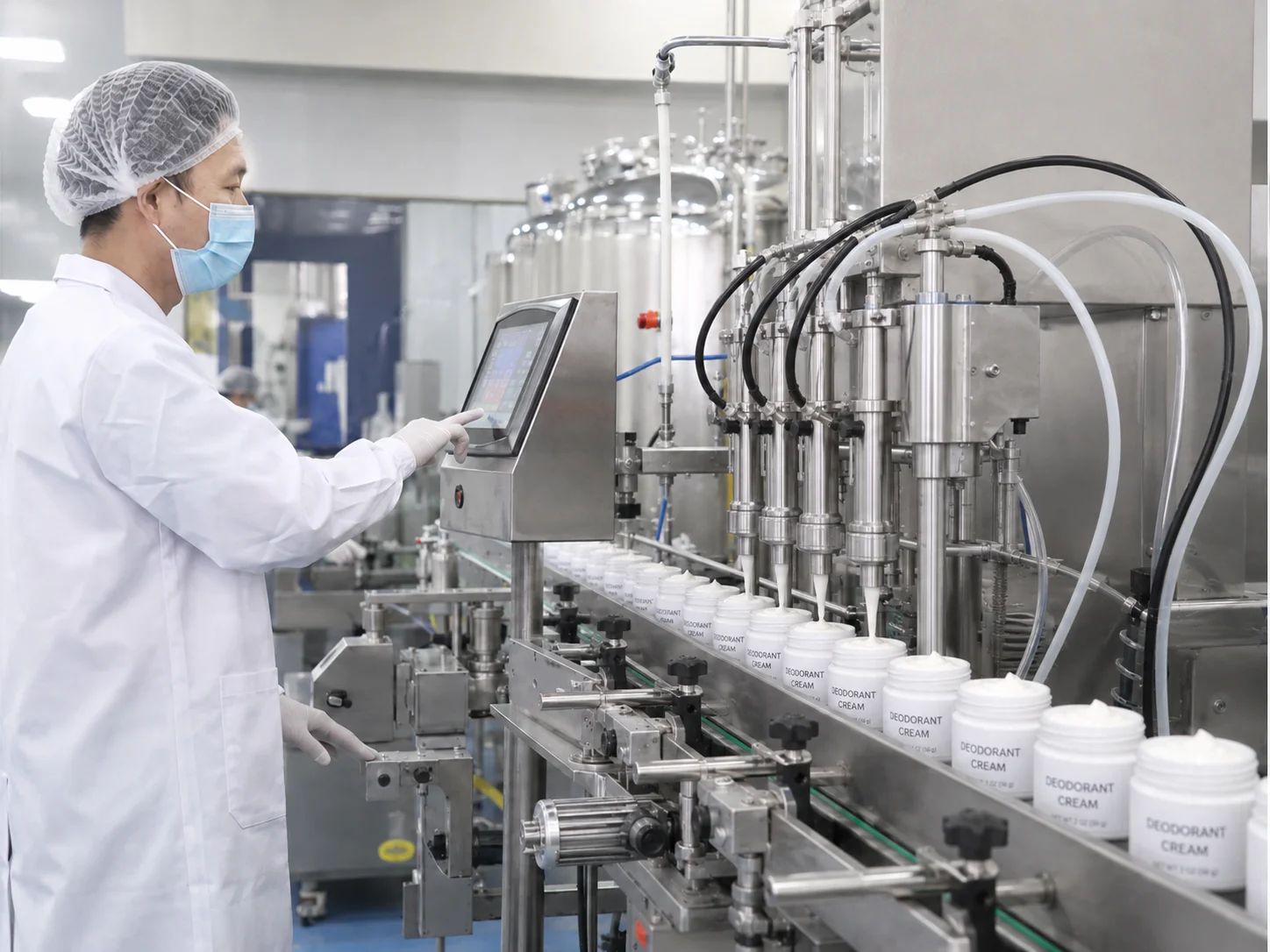 A factory worker in a white lab coat operates a touchscreen control panel for an automated deodorant cream production line.